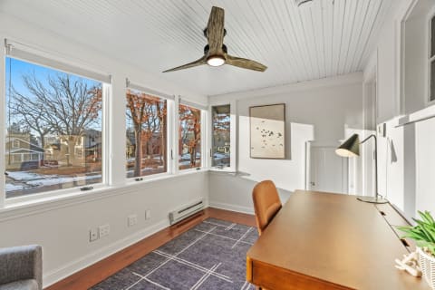 A bright workspace with large windows, a wooden desk, and seasonal views.