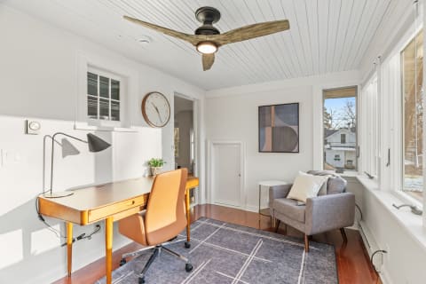 Bright workspace combining mid-century charm and modern comfort, featuring a desk, chair, and cozy reading nook.