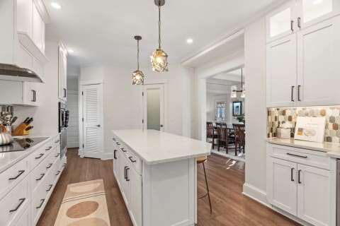 Modern kitchen featuring white cabinetry, pendant lights, and an island with a white countertop.