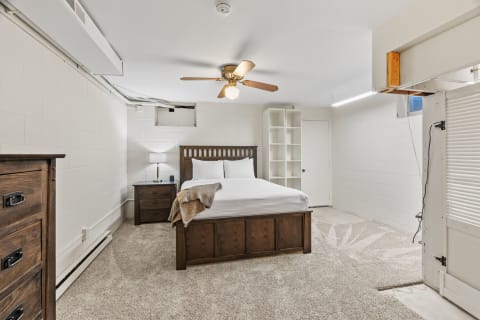 A cozy basement bedroom featuring a wooden bed, soft carpet, and natural light.