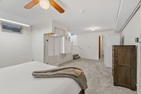 Cozy bedroom with a ceiling fan, neutral walls, and plush carpeting.