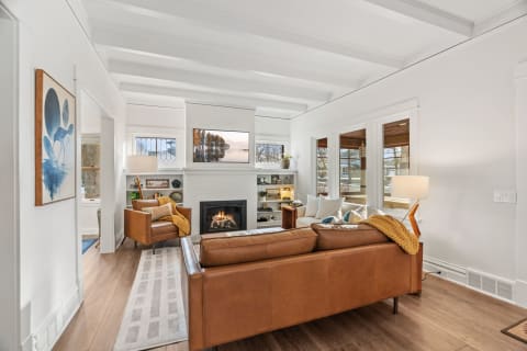 A modern living room featuring leather seating, a fireplace, and artistic decor.
