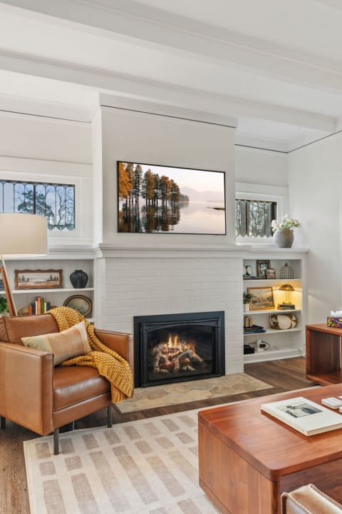 Cozy living room with leather armchair, fireplace, and built-in shelves filled with decor.