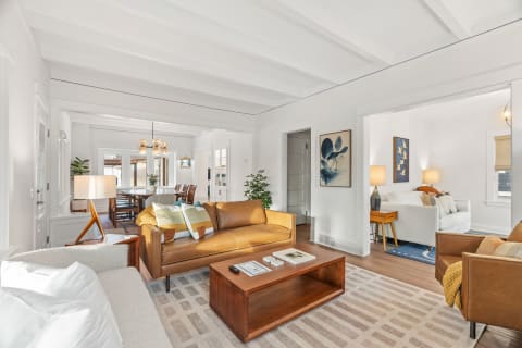 A stylish and cozy living room with leather furniture, wooden accents, and soft lighting.