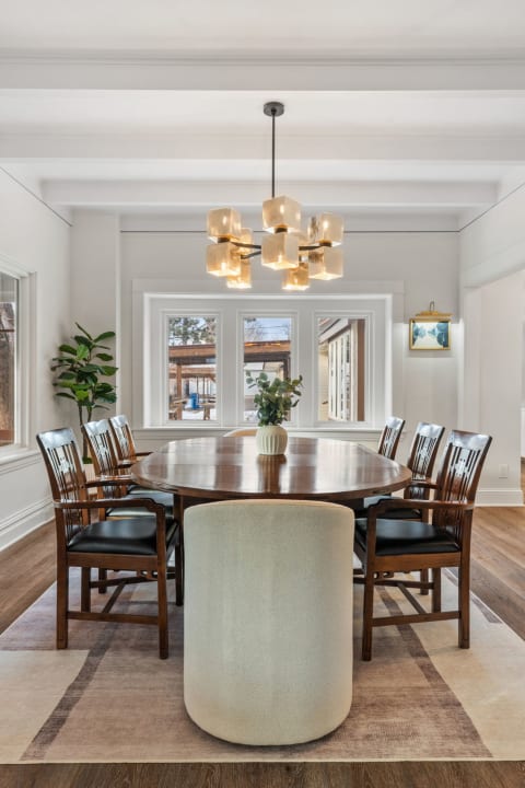 A sophisticated dining room featuring a round table, wooden chairs, and a decorative chandelier.