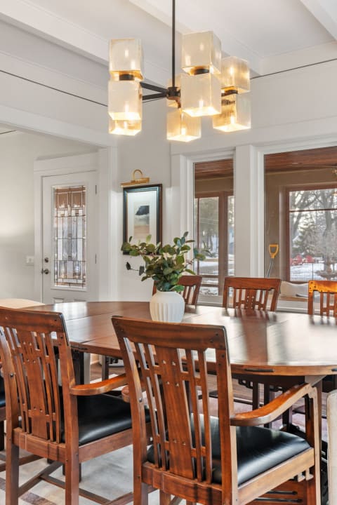 Cozy dining room with wooden table and elegant pendant lighting.