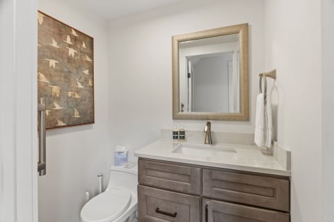 A stylish bathroom featuring a wooden vanity, decorative mirror, and artwork on the wall.