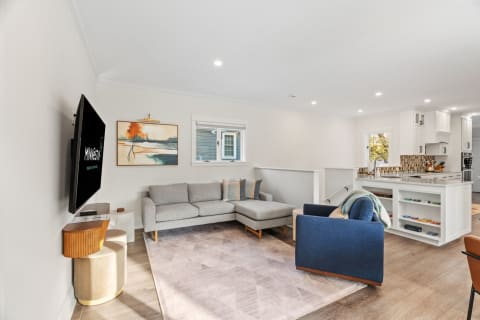 Open-plan living space with a gray sectional sofa, a blue accent chair, and a modern kitchen in the background.
