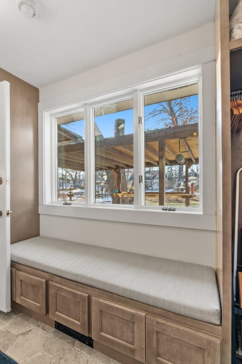Interior view of a cozy window seat with a patterned cushion overlooking a snowy courtyard.