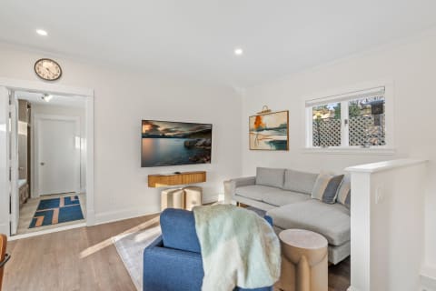 Contemporary living room with gray sectional sofa, blue armchair, and wall-mounted TV.