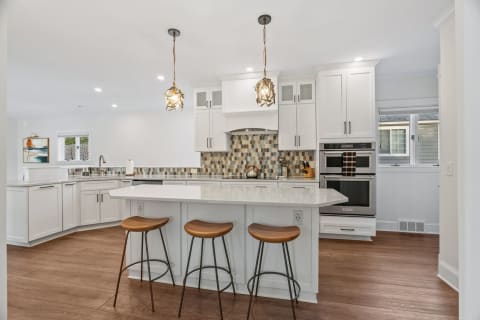 Modern kitchen featuring white cabinets, an island with seating, and pendant lights.