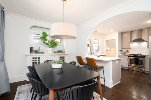 Stylish dining room featuring a black table, elegant chairs, and a modern kitchen in the background.