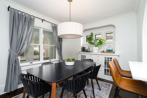 A contemporary dining room featuring a dark table, black chairs, and stylish decor with plants.