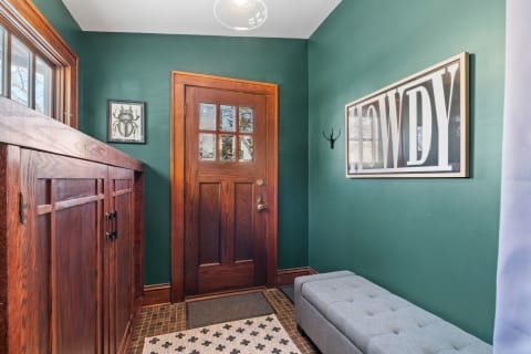 Cozy entryway featuring dark green walls, a wooden door, and decorative elements.