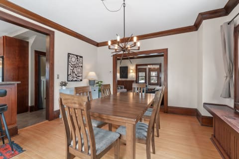 Dining room with wooden table, modern chandelier, and decorative artwork.
