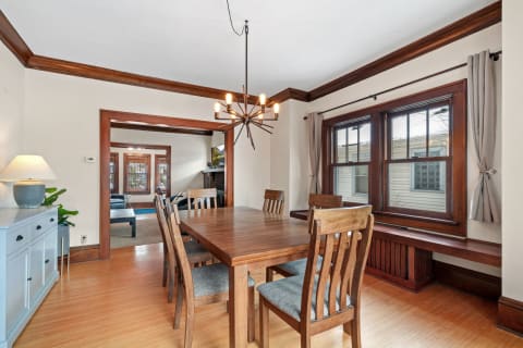 A cozy dining room featuring a wooden table, chairs, and a unique chandelier.