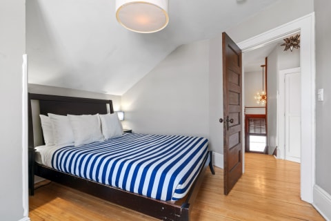 A cozy bedroom featuring a stripped mattress cover, soft lighting, and an angled ceiling.