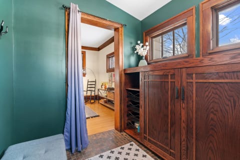 Stylish entryway with teal walls, a wooden cabinet, and curtains.