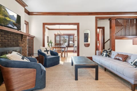 A cozy living room featuring a light gray sofa, blue accent chairs, and a rustic fireplace.