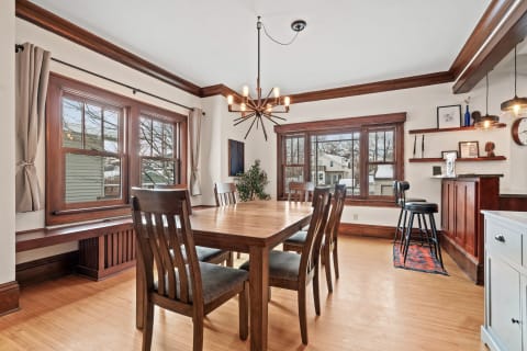 A well-decorated dining room with a wooden table, chairs, and large windows.