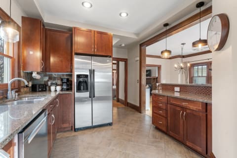 A contemporary kitchen featuring wood cabinets, stainless steel refrigerator, and granite countertops.