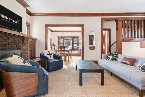 Inviting living room featuring a gray sofa, blue armchairs, and a rustic coffee table under a mounted TV.