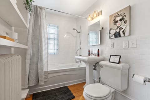 A well-designed bathroom with white tiles, a bathtub, a prominent mirror, and neatly arranged toiletries.