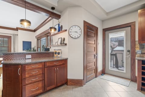 Cozy kitchen featuring granite countertop, wooden cabinets, and modern light fixtures.