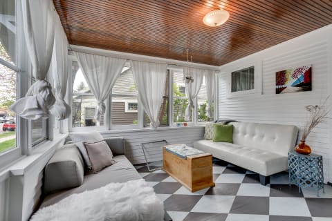 Cozy sunroom featuring a mix of modern and classic decor with large windows and stylish furniture.