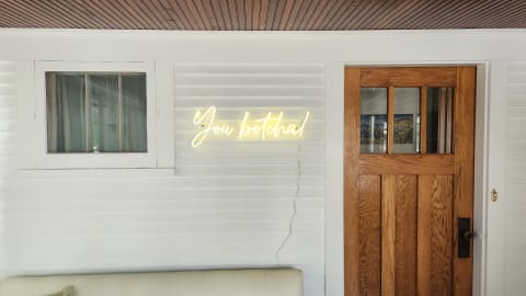 An indoor area with a neon sign that says 'You betcha!' and a wooden door.