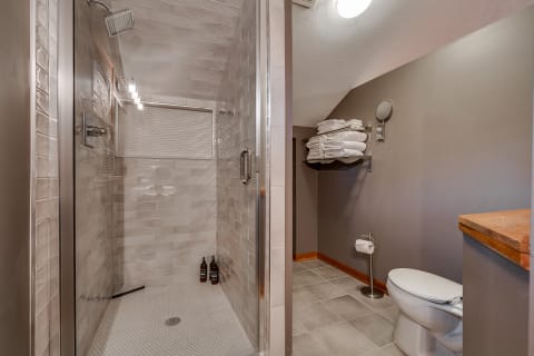 Modern bathroom featuring a glass shower, neatly stacked towels, and a white toilet.