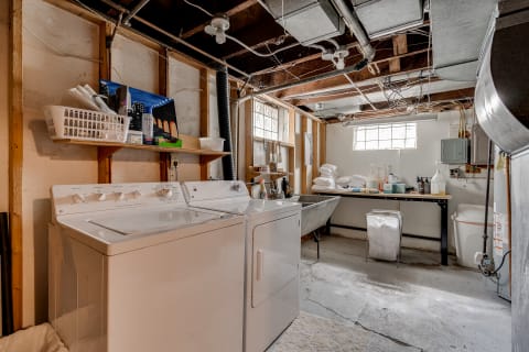 Laundry room in a basement with a washing machine, dryer, and storage shelves