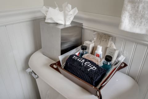 Personal care items and a tissue box on a bathroom toilet tank.