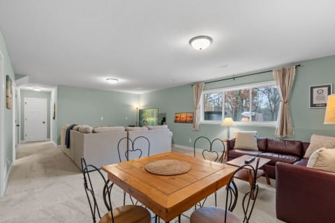 Interior of a cozy living room featuring a sectional sofa and a wooden dining table.