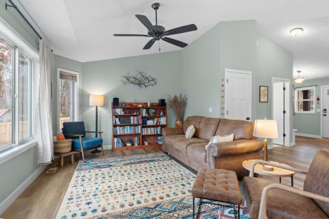 Inviting living room featuring a leather sofa, bookshelf, and blue accent chair.