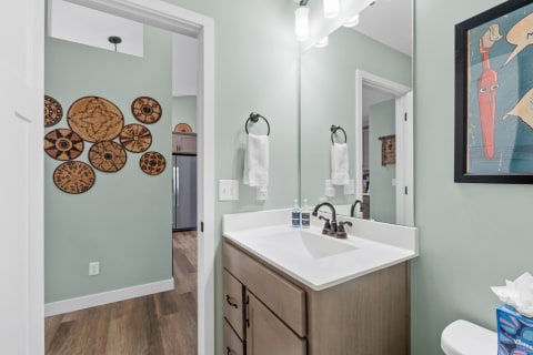 A modern bathroom featuring a sink, decorative baskets on the wall, and wood flooring.