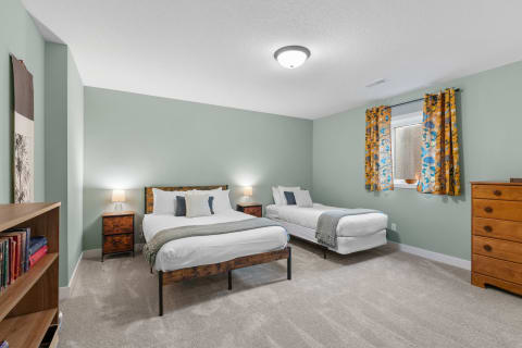 A modern bedroom featuring two beds, warm lighting, and floral curtains.