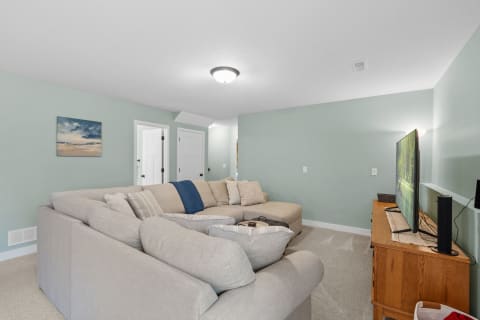 Cozy living room featuring a sectional sofa, entertainment unit, and light green walls.