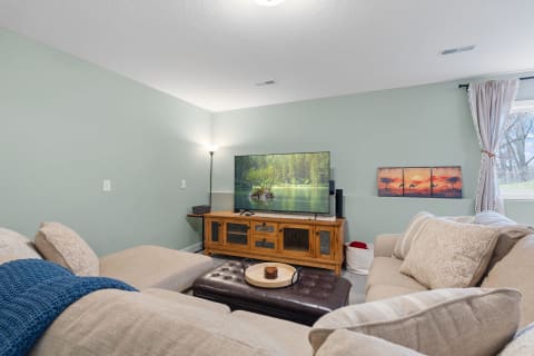 Cozy living room with a TV, sofa, ottoman, and decorative wall art.