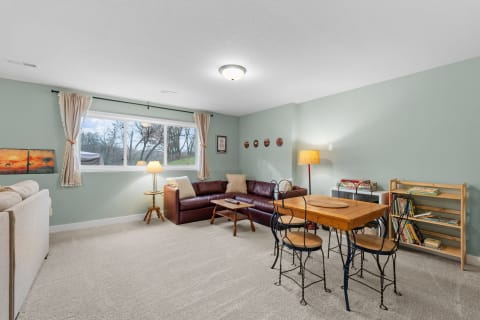 Cozy living room with a sofa, wooden table, and large window letting in natural light.
