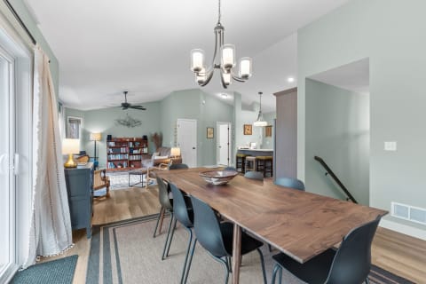Interior view of a dining area leading into a living space with a wooden dining table and gray decor.