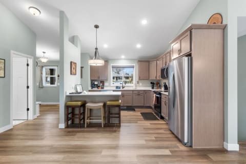 A contemporary kitchen featuring light wood cabinets, stainless steel appliances, and a spacious layout.