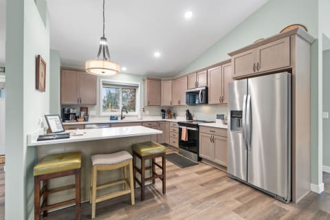 Modern kitchen with light cabinets, stainless steel appliances, and an island with seating.