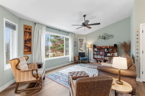Cozy living room with a large window, a sofa, bookshelves, and decorative elements.