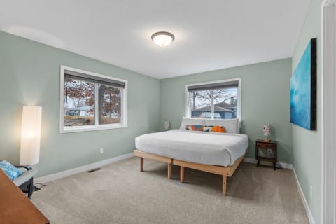 Modern bedroom with a green wall, double bed, and natural light from windows.