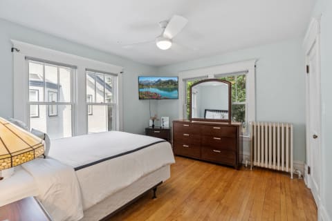 Cozy bedroom featuring hardwood floors, large windows, and elegant furnishings.