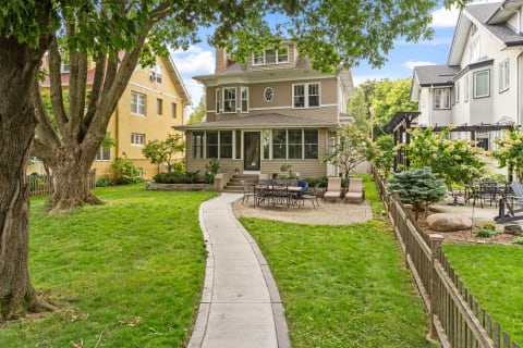 A beautiful home with a spacious yard and patio, featuring a curved pathway and greenery.