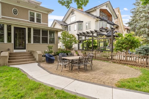 A cozy outdoor space featuring a patio with a dining table, surrounded by well-kept gardens and neighboring homes.