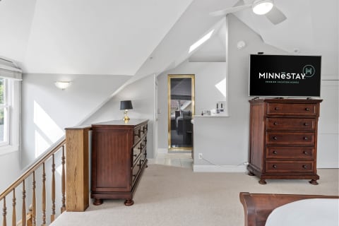 Interior view of an upstairs bedroom with wooden furniture and slanted ceilings, featuring a TV and a cozy ambiance.