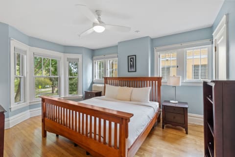 A tranquil bedroom featuring a wooden bed, blue walls, and large windows.